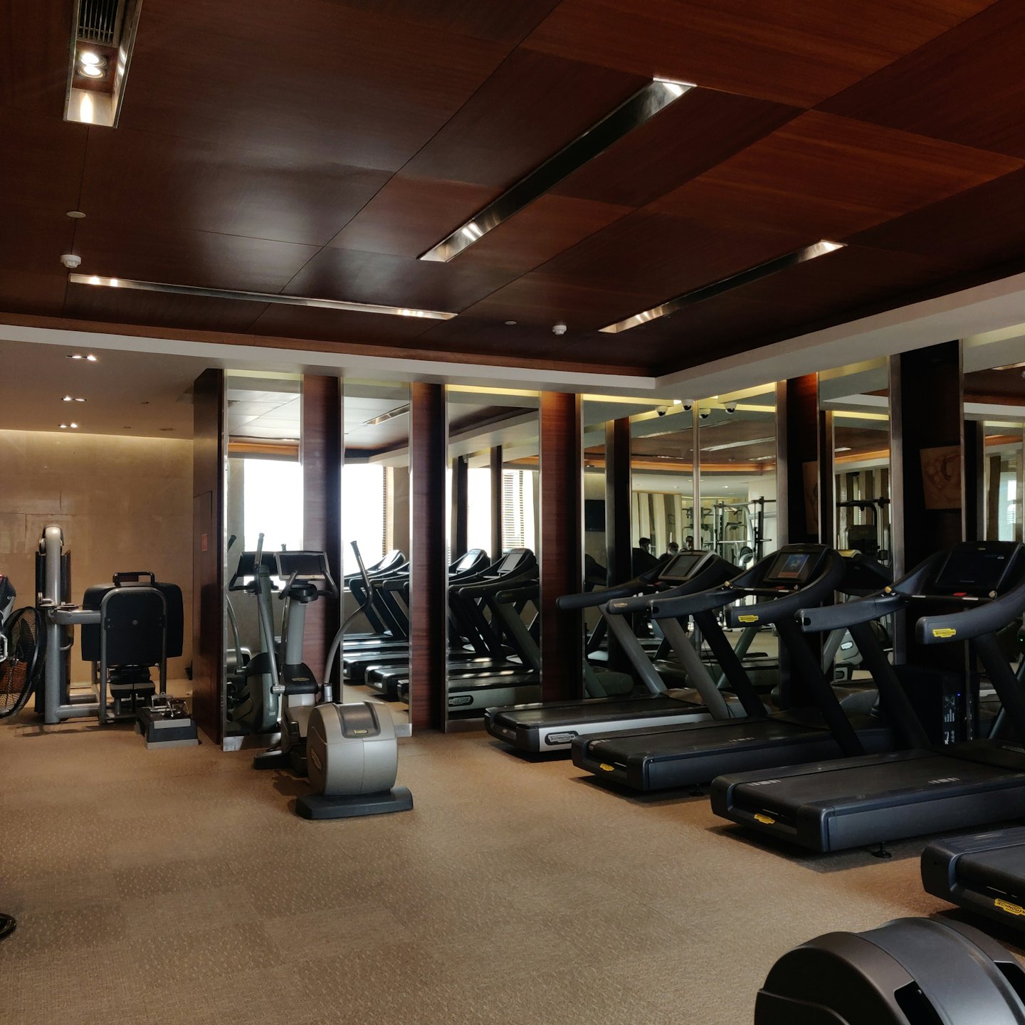 Rows of exercise equipment inside a modern fitness center.