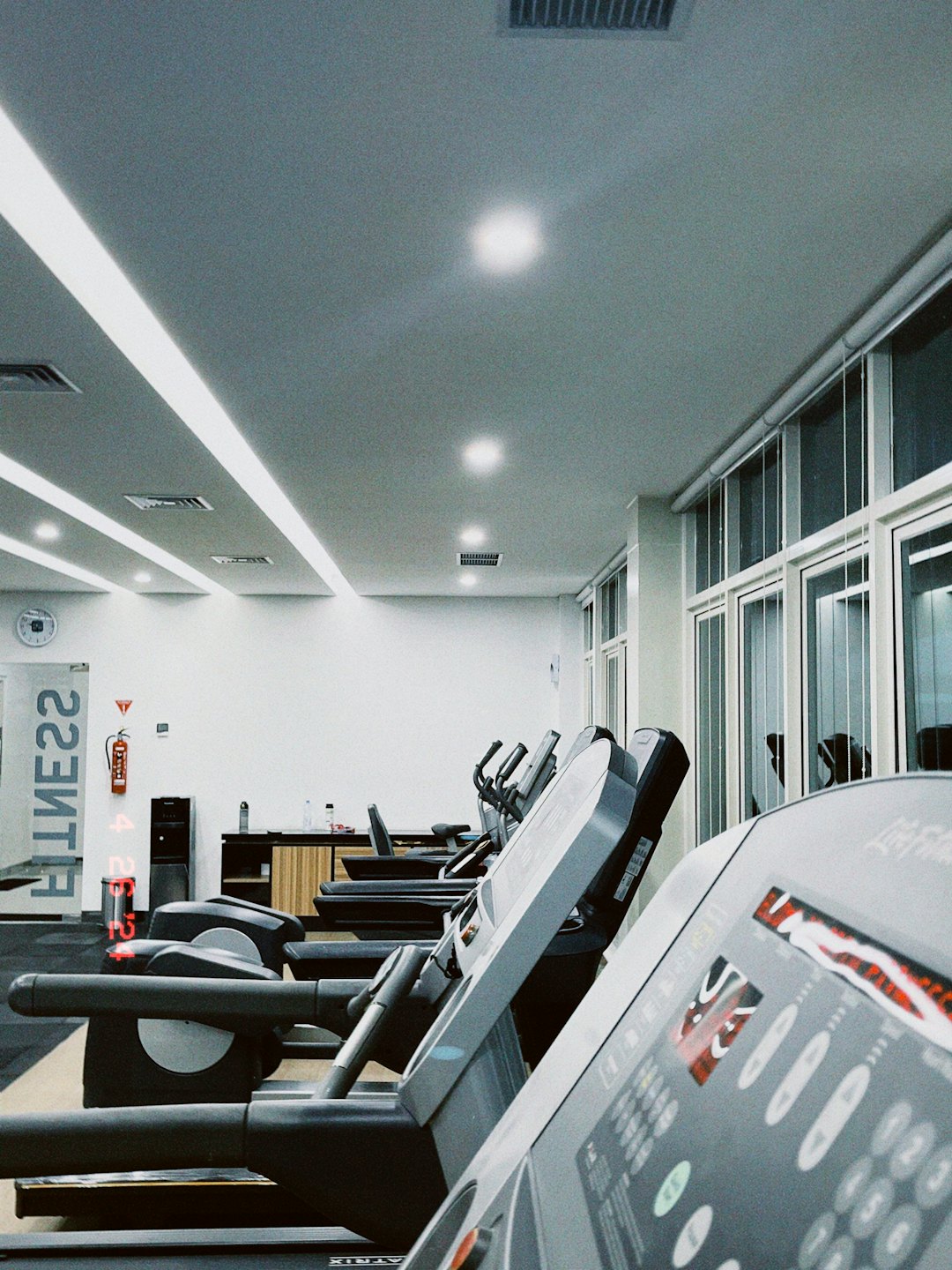 Rows of treadmills in a modern, well-lit gym.